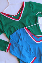 Close view of two Zofina vintage 70s long sleeve leotards in green, and blue on white hangers.