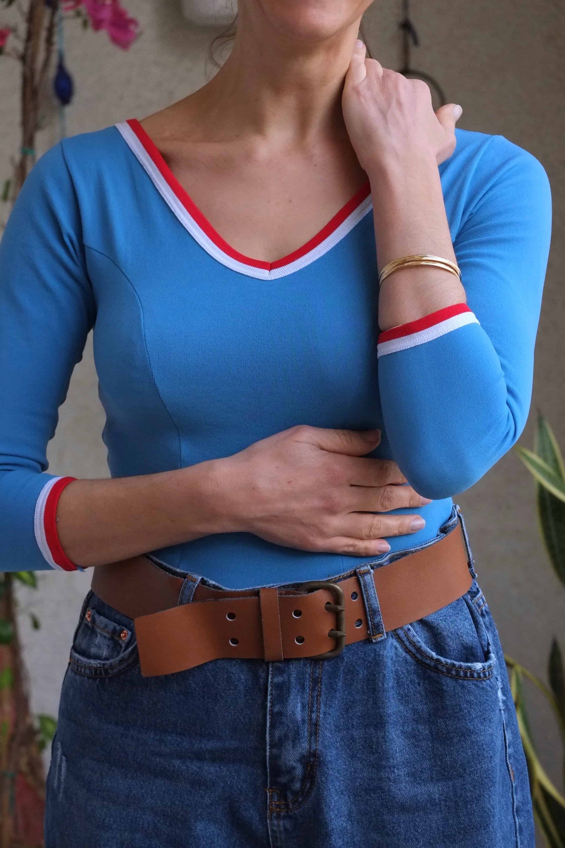 Woman wearing a vintage blue Zofina leotard with a leather belt and denim jeans.