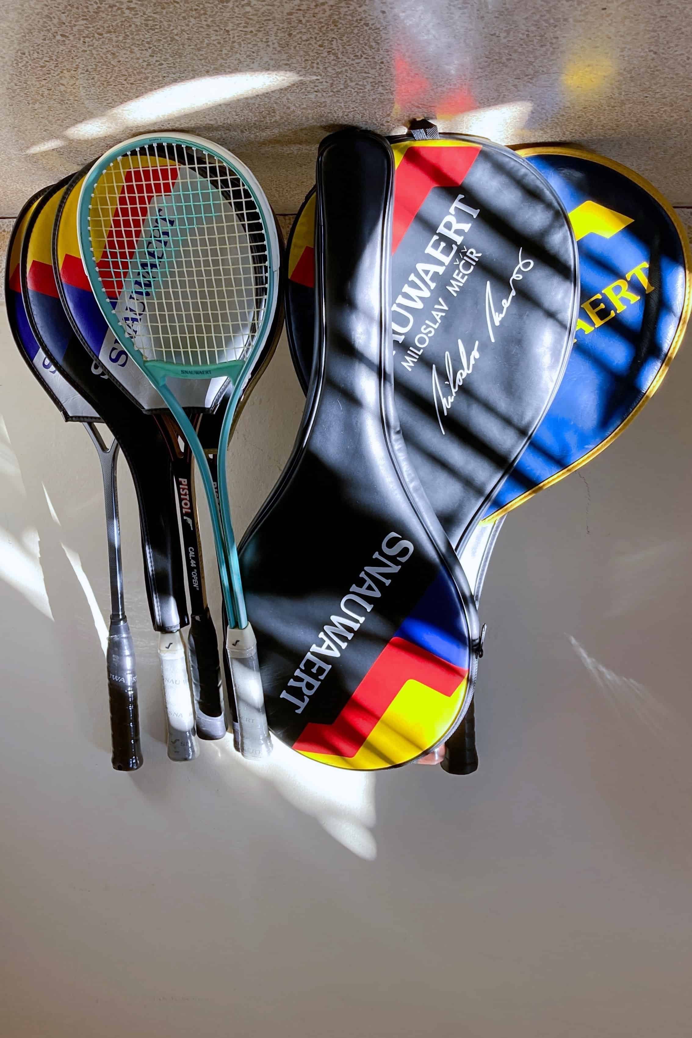A collection of vintage tennis rackets set against a wall.