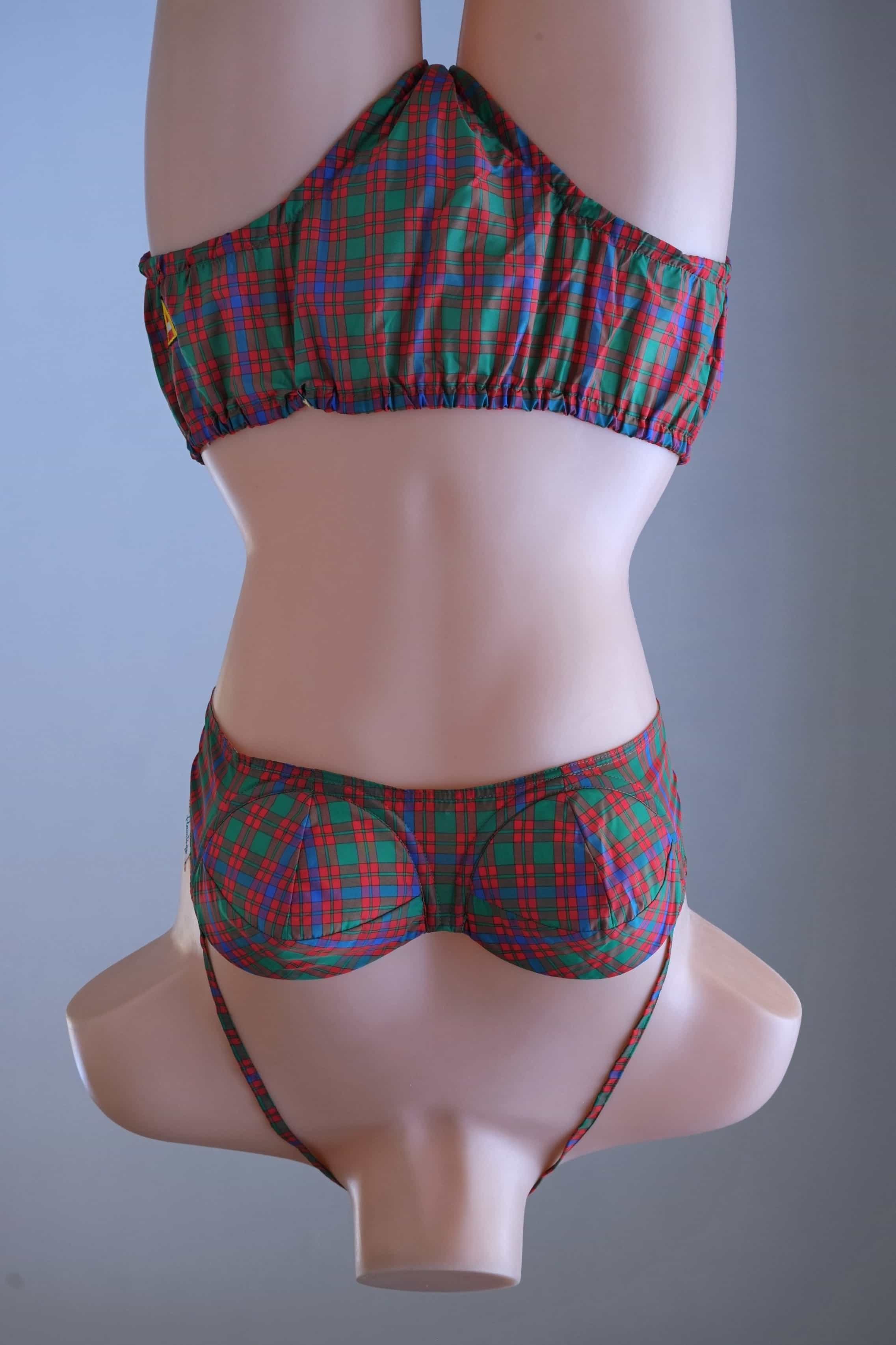 Full front view of a vintage 1960s red, green, and blue tartan plaid two-piece bikini set with a halter top and high-waisted bottoms on a female mannequin.