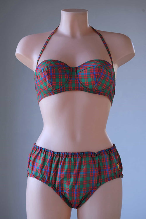 Full front view of a vintage 1960s red, green, and blue tartan plaid two-piece bikini set with a halter top and high-waisted bottoms on a female mannequin.