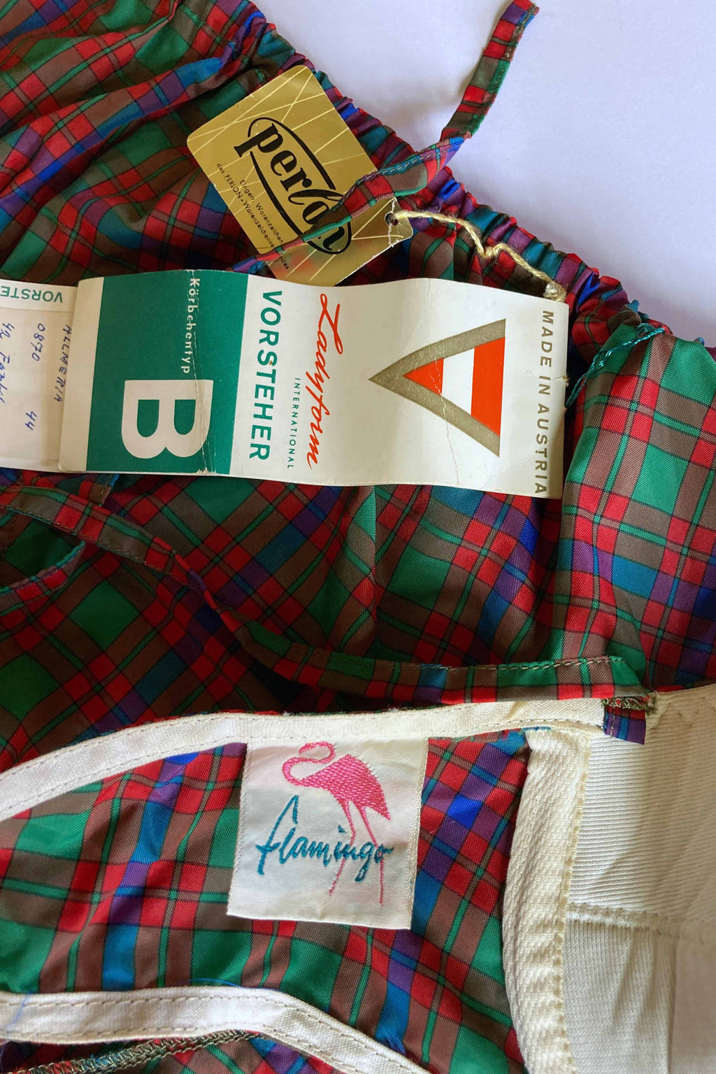 Detail shot of the vintage bikini showing the stitched pink Flamingo woven label alongside original paper Vorsteher and Perlon paper hang tags.