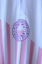 Close-up of Löffler polo collar, two-button placket and purple Championship Season’s Best badge over pink stripes