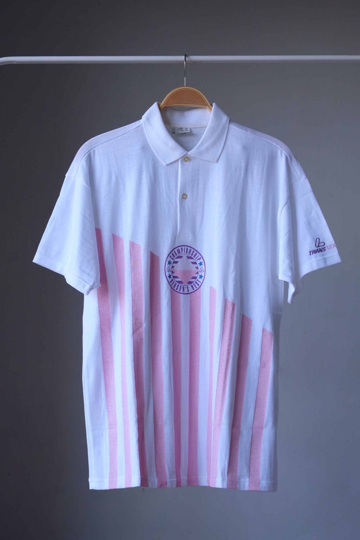 Löffler 90s men’s tennis polo in white with pink vertical stripes and a purple Championship Season’s Best badge, front view