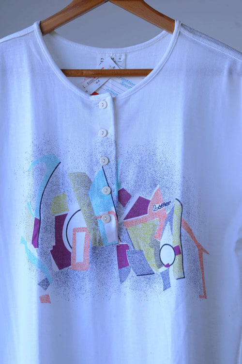 Close-up of the buttoned placket and Memphis-style graphic in lilac, sky blue, sage and orange on a white Löffler 90s top