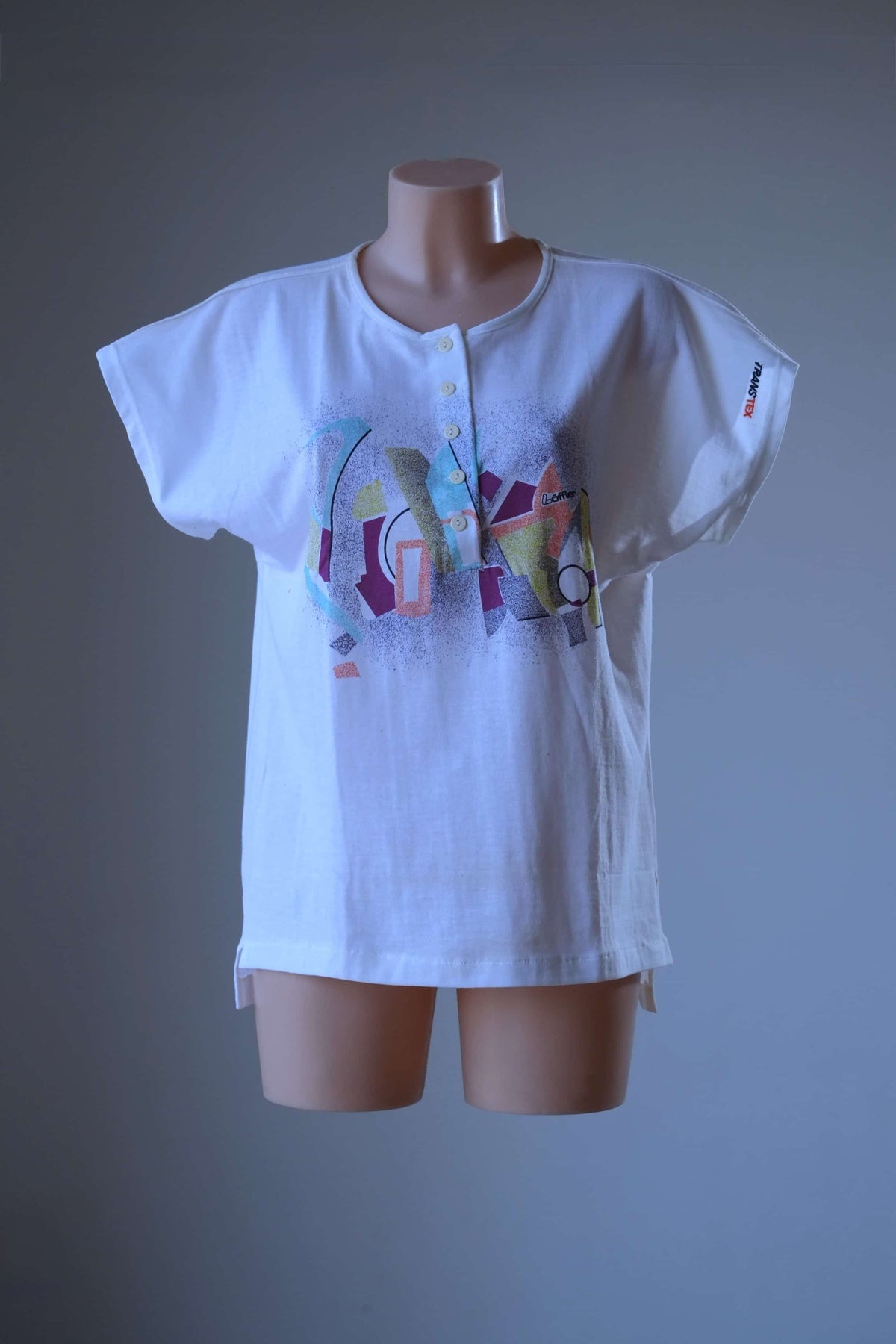Front view of white Löffler 90s women’s henley top on a mannequin with cap sleeves, five-button placket, Memphis-style graphic and Transtex sleeve embroidery