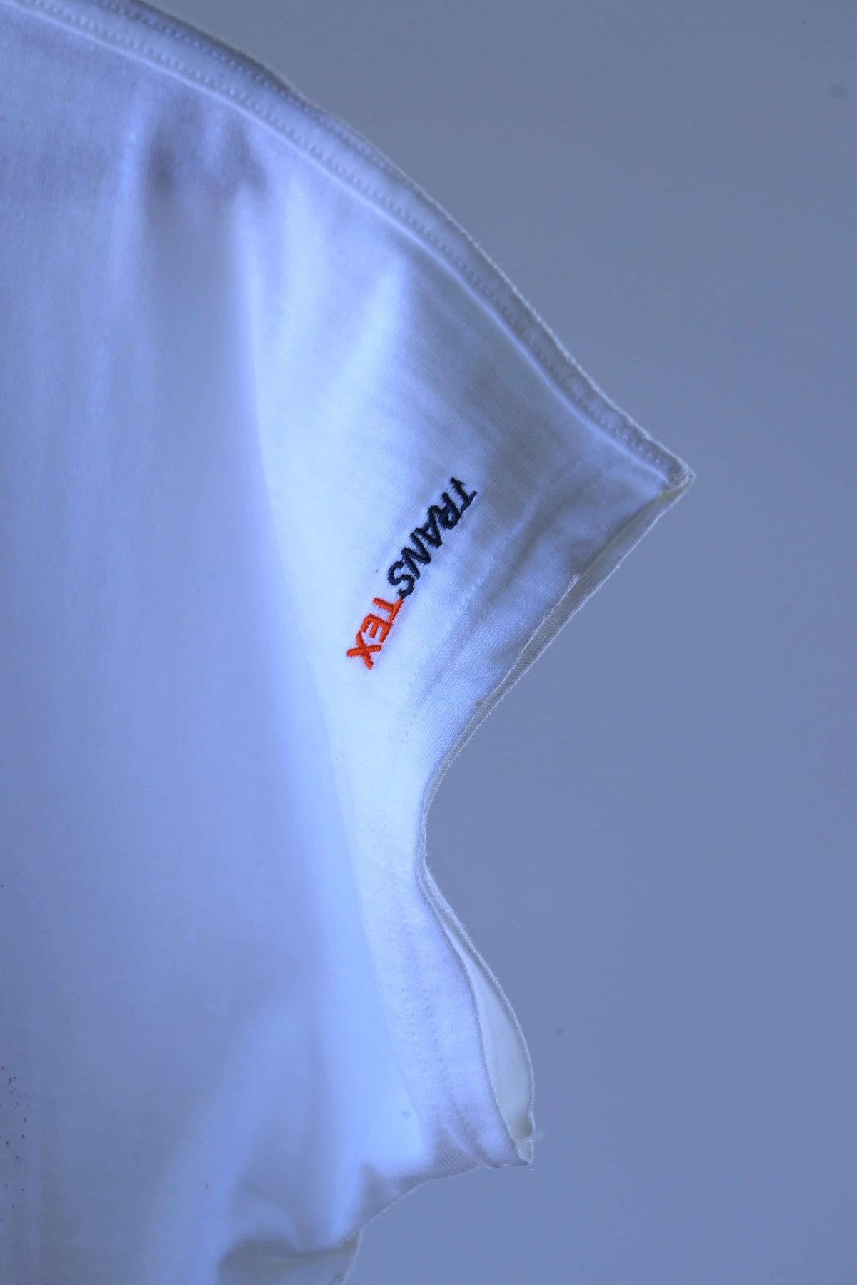 Close-up of the cap sleeve with orange and navy embroidered Transtex logo running vertically along the sleeve