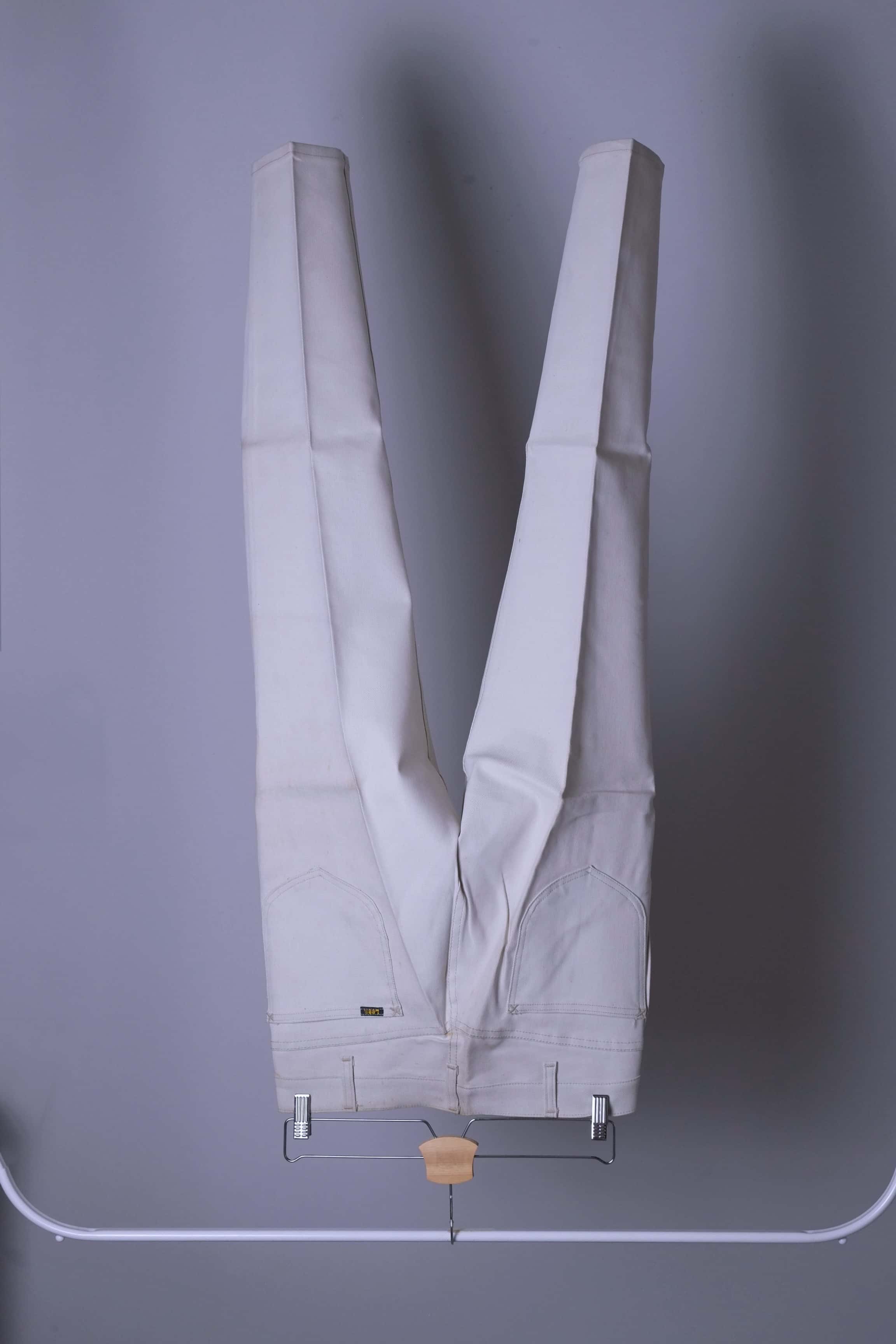 NOS Vintage Lee Leens Lastic Stretch trousers in beige color, back view, hanging on a metal rack.