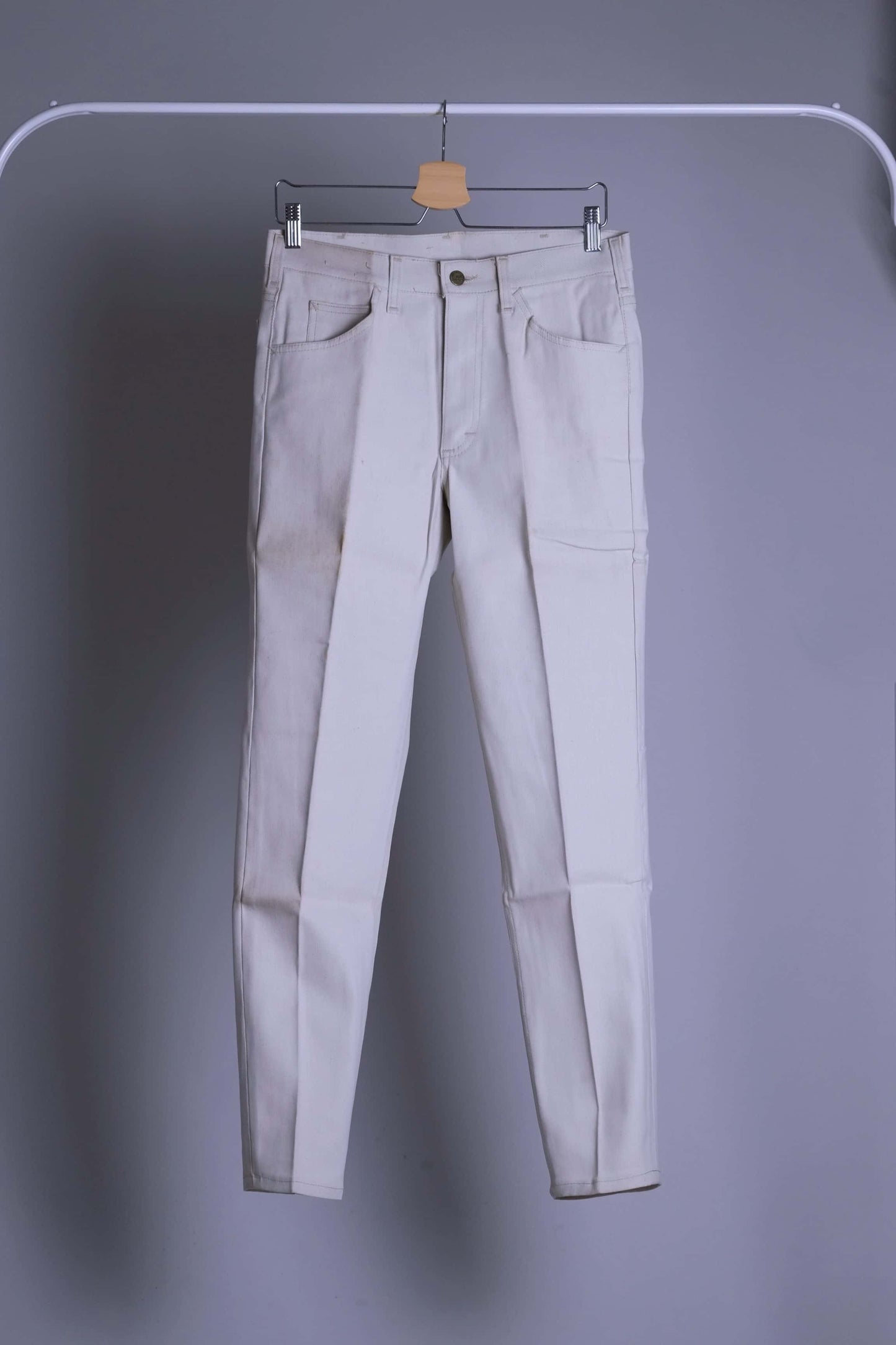 NOS Vintage Lee Leens Lastic Stretch trousers in beige color, front view, hanging on a metal rack.