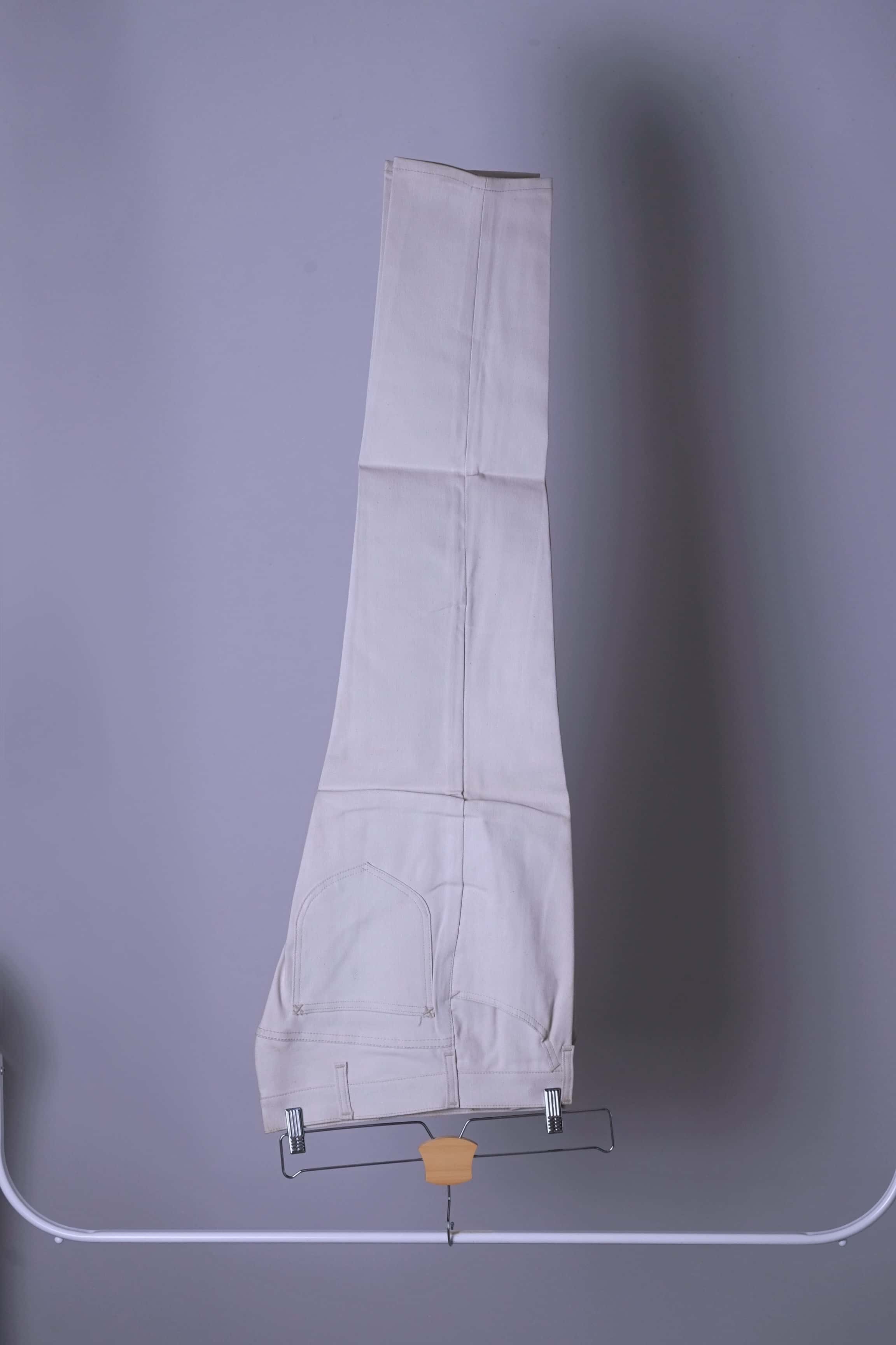 NOS Vintage Lee Leens Lastic Stretch trousers in beige color, folded, hanging on a metal rack.