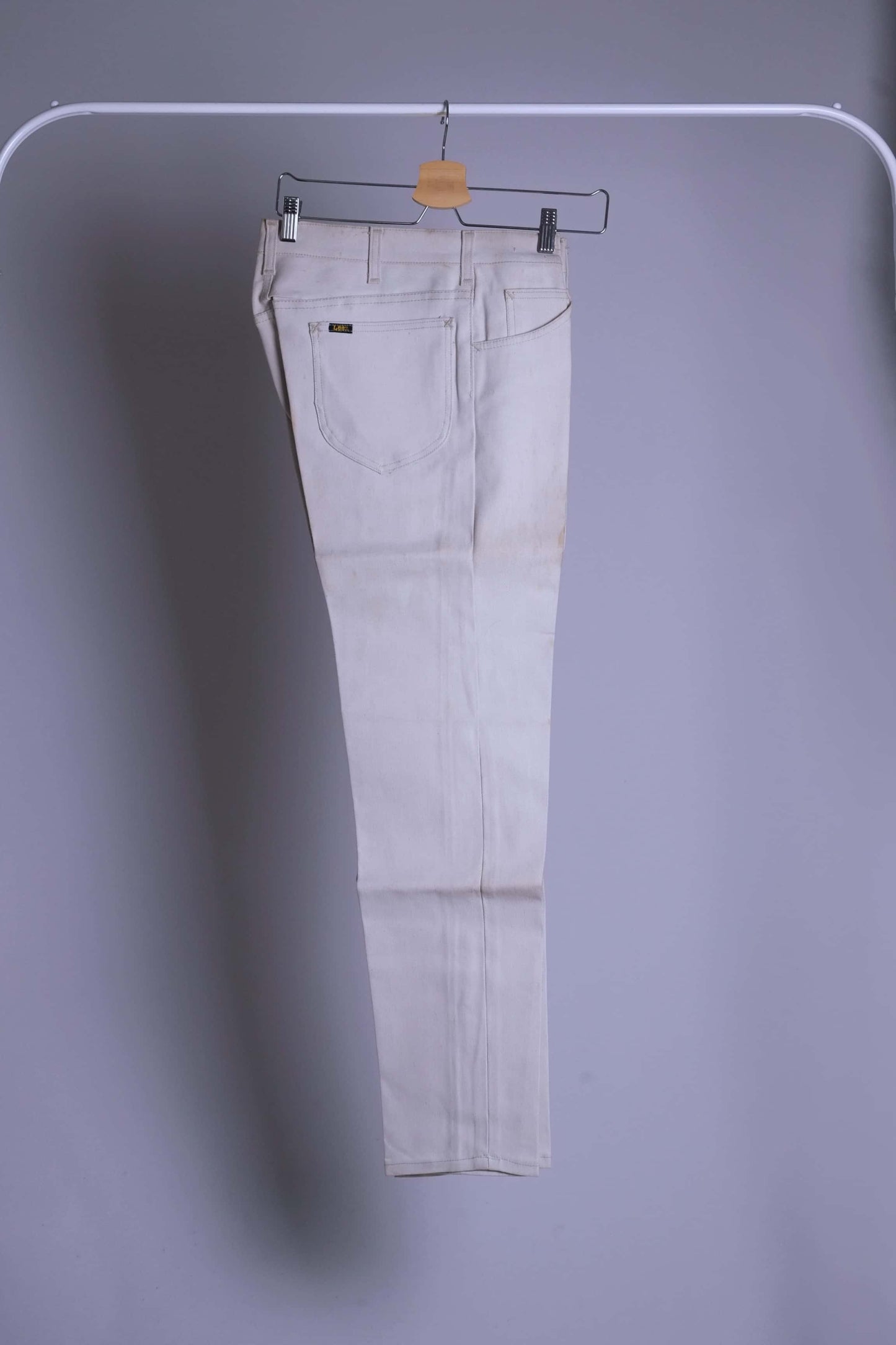 NOS Vintage Lee Leens Lastic Stretch trousers in beige color, side view, hanging on a metal rack.