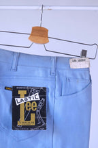 Close-up detail shot of the back of the NOS 70s Lee Leens in light blue, showing the original white 'Lee Leens' label and the black, yellow, and red 'Lastic Lee Stretch Denim' product hang tag.