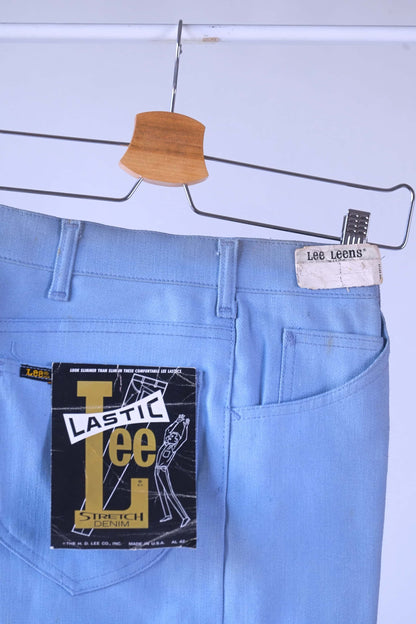 Close-up detail shot of the back of the NOS 70s Lee Leens in light blue, showing the original white 'Lee Leens' label and the black, yellow, and red 'Lastic Lee Stretch Denim' product hang tag.