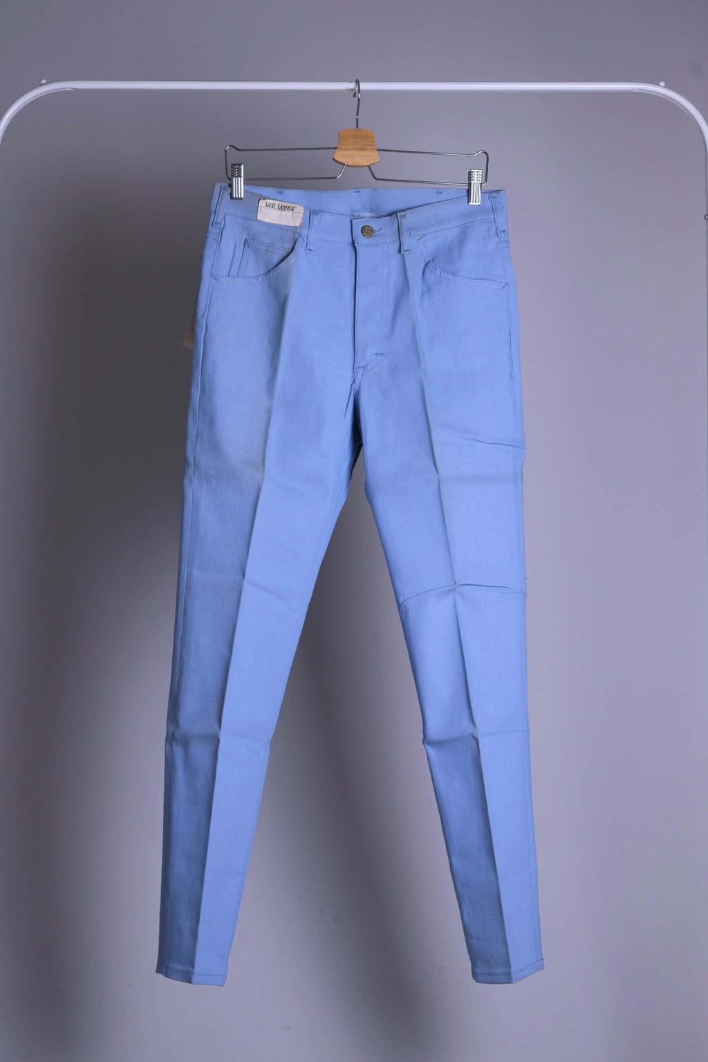 Front view of NOS 70s Lee Leens Lastic Stretch denim trousers in light sky blue, shown hanging on a rack.