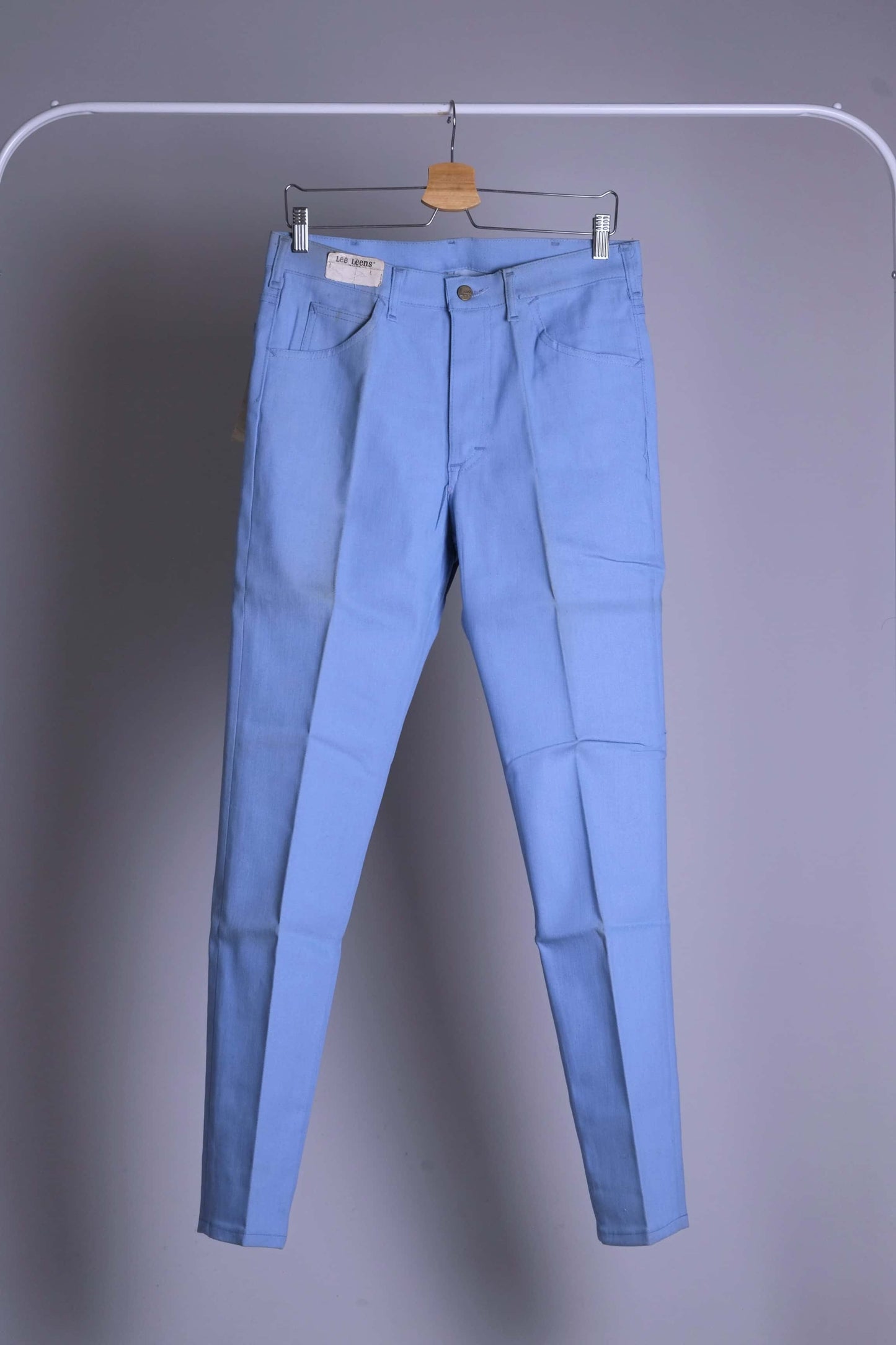 Front view of NOS 70s Lee Leens Lastic Stretch denim trousers in light sky blue, shown hanging on a rack.