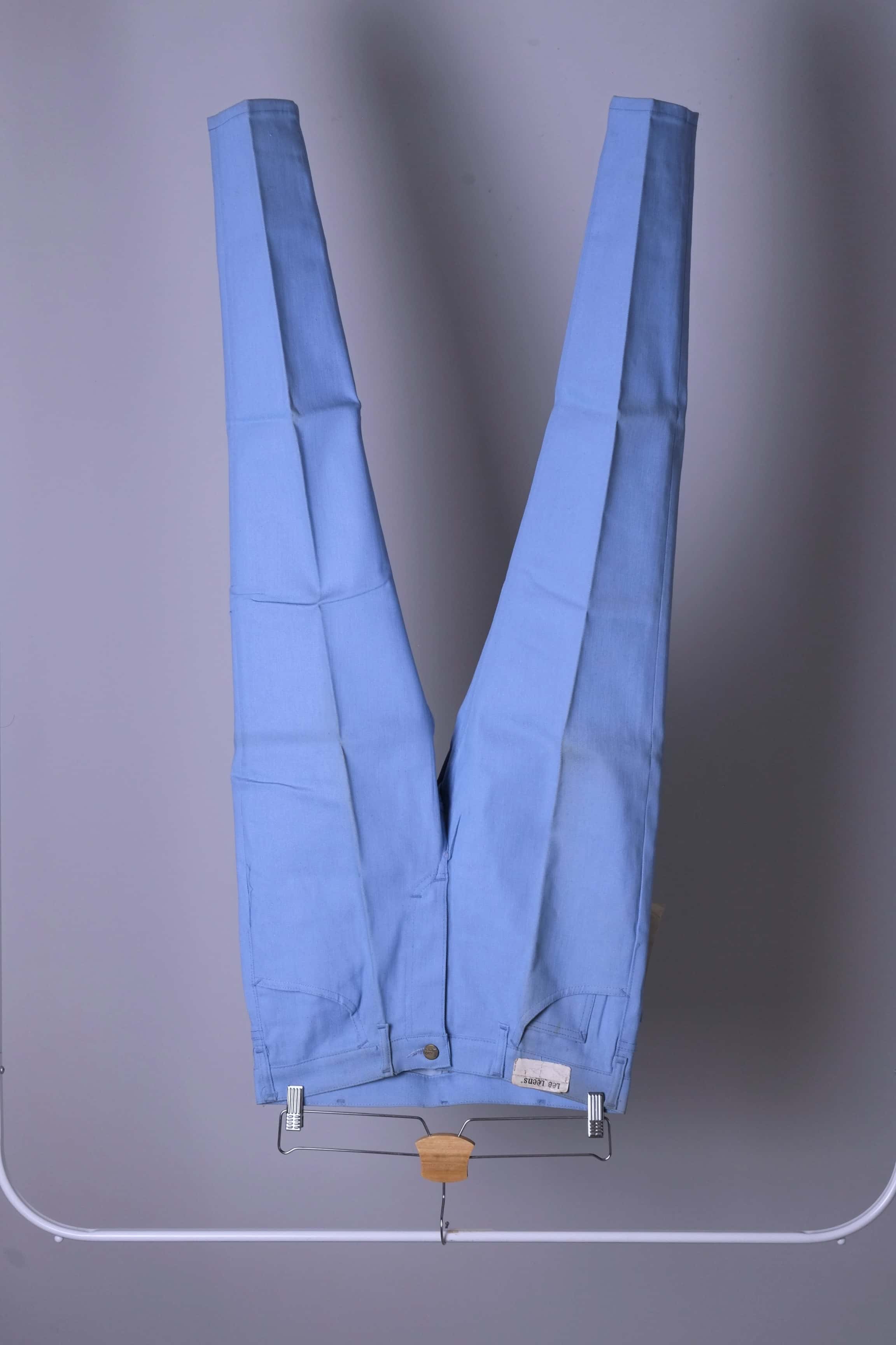 Front view of NOS 70s Lee Leens Lastic Stretch denim trousers in light sky blue, shown hanging on a rack.