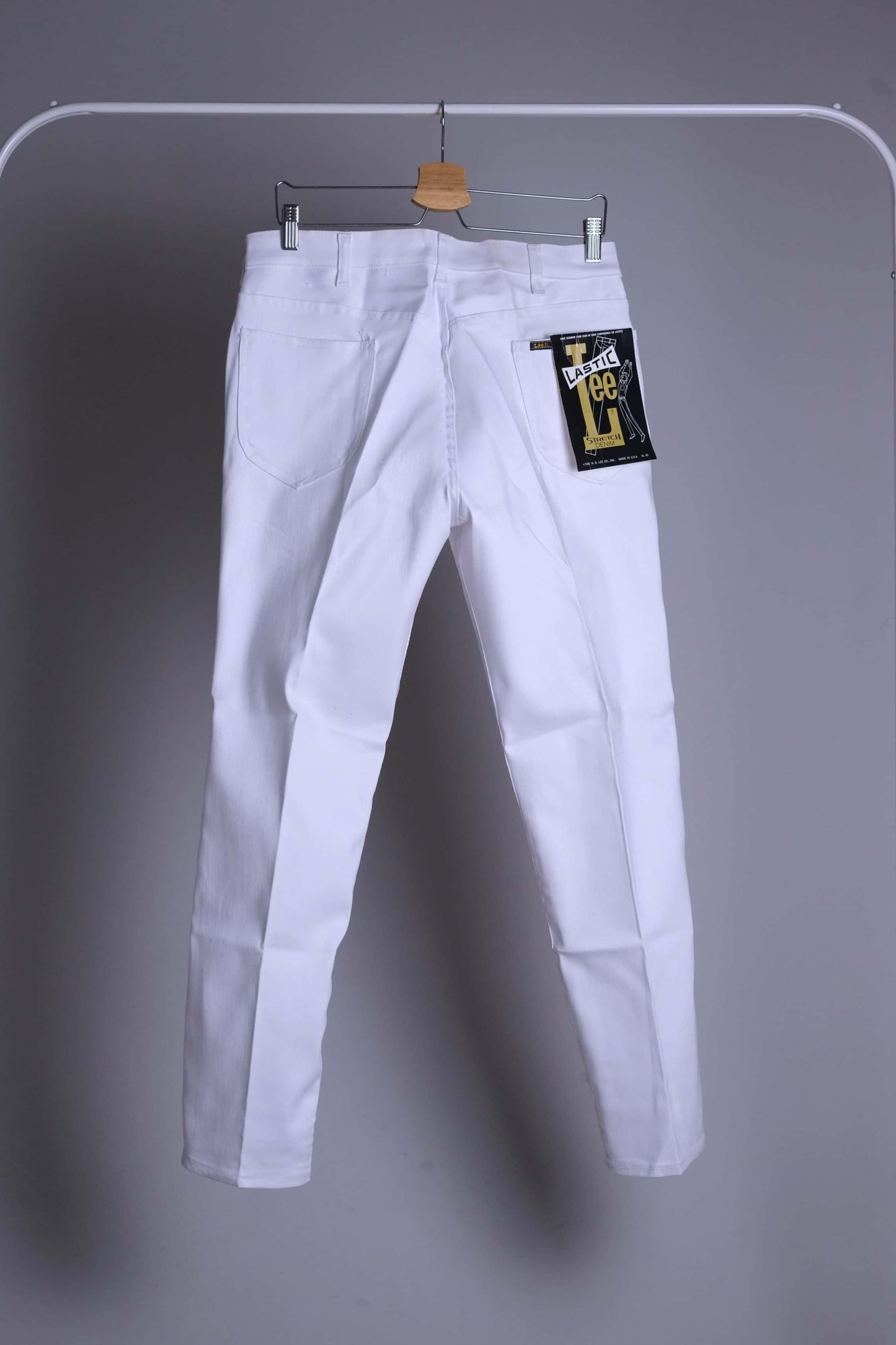 NOS Lee Leens Lastic Stretch trousers in white, back view, with the original 'Lastic Lee' product tag clearly visible on the right back pocket.