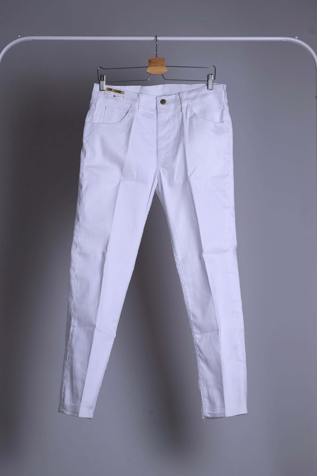 Clean, full-front view of NOS 70s white Lee Leens stretch trousers hanging on a rack.