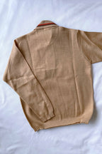 The back of a beige pure new wool knit polo sweater with orange and brown striped collar detailing flat-laid on a white background.