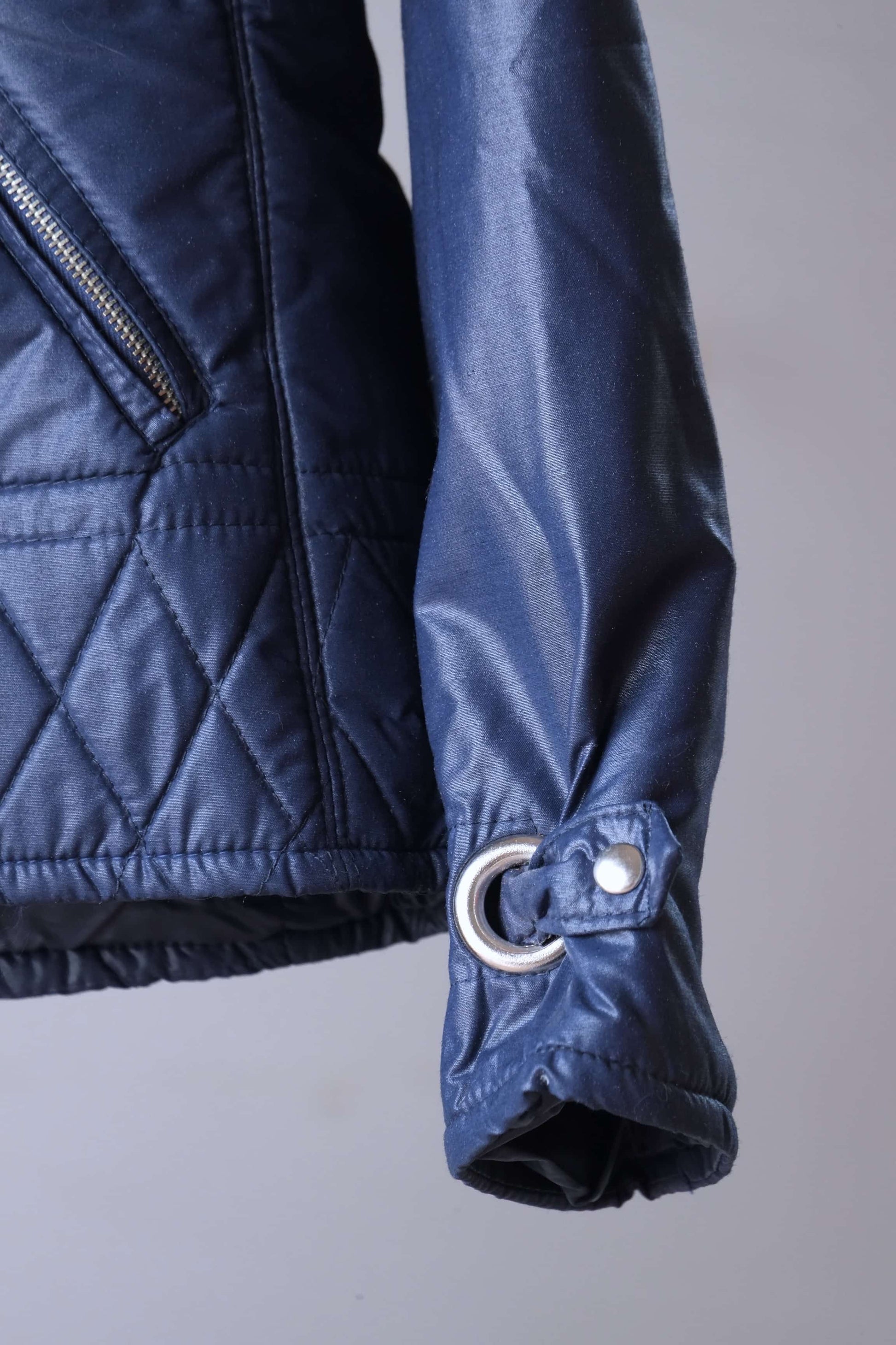 Close up view of sleeve of Vintage navy 2-piece ski suit on hanger